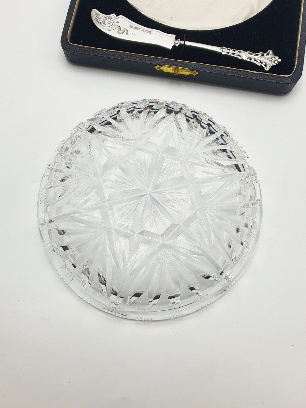 A circular cut crystal butter dish and a hallmarked sterling silver spreader presented inside a fitted black box. View VII