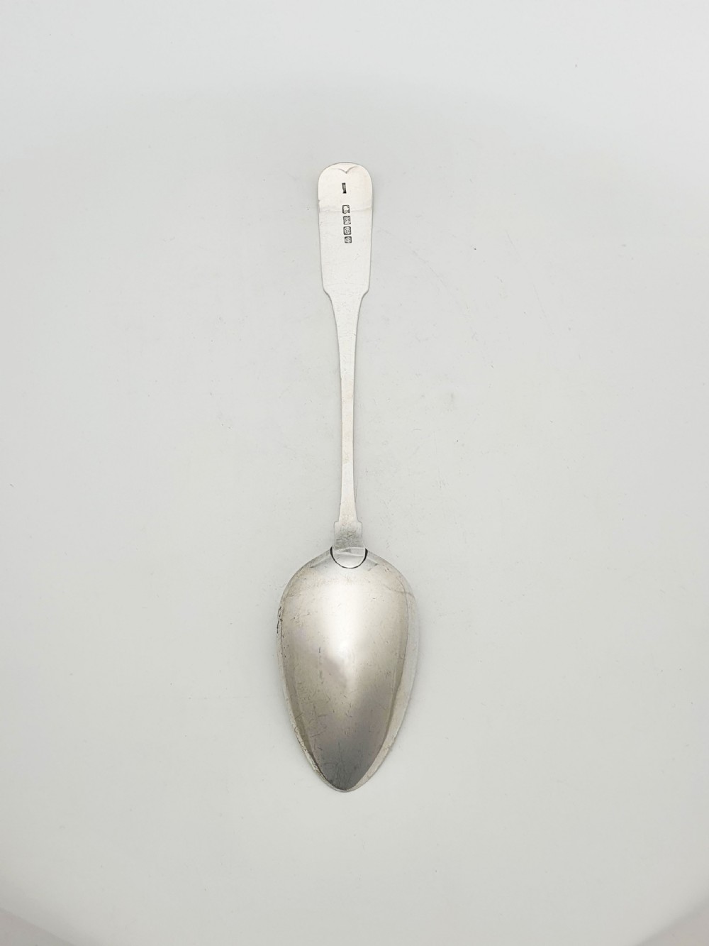 A Georgian sterling silver basting spoon featuring a long flat stem and oval bowl against a plain light background. View II