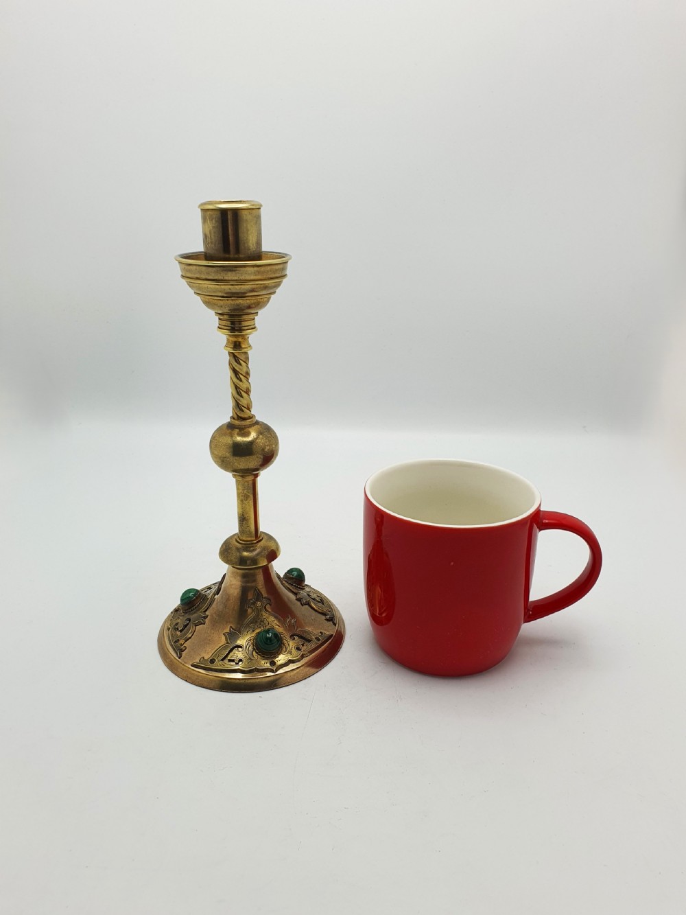 A pair of Victorian Gothic Revival brass candlesticks featuring spiral stems, spherical central knops, and circular bases with inset green cabochon stones. View X