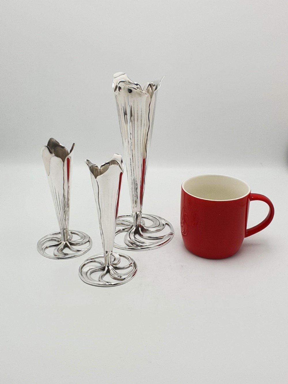 A set of three silver-plated trumpet vases with fluted rims and openwork swirl bases of varying heights. View III