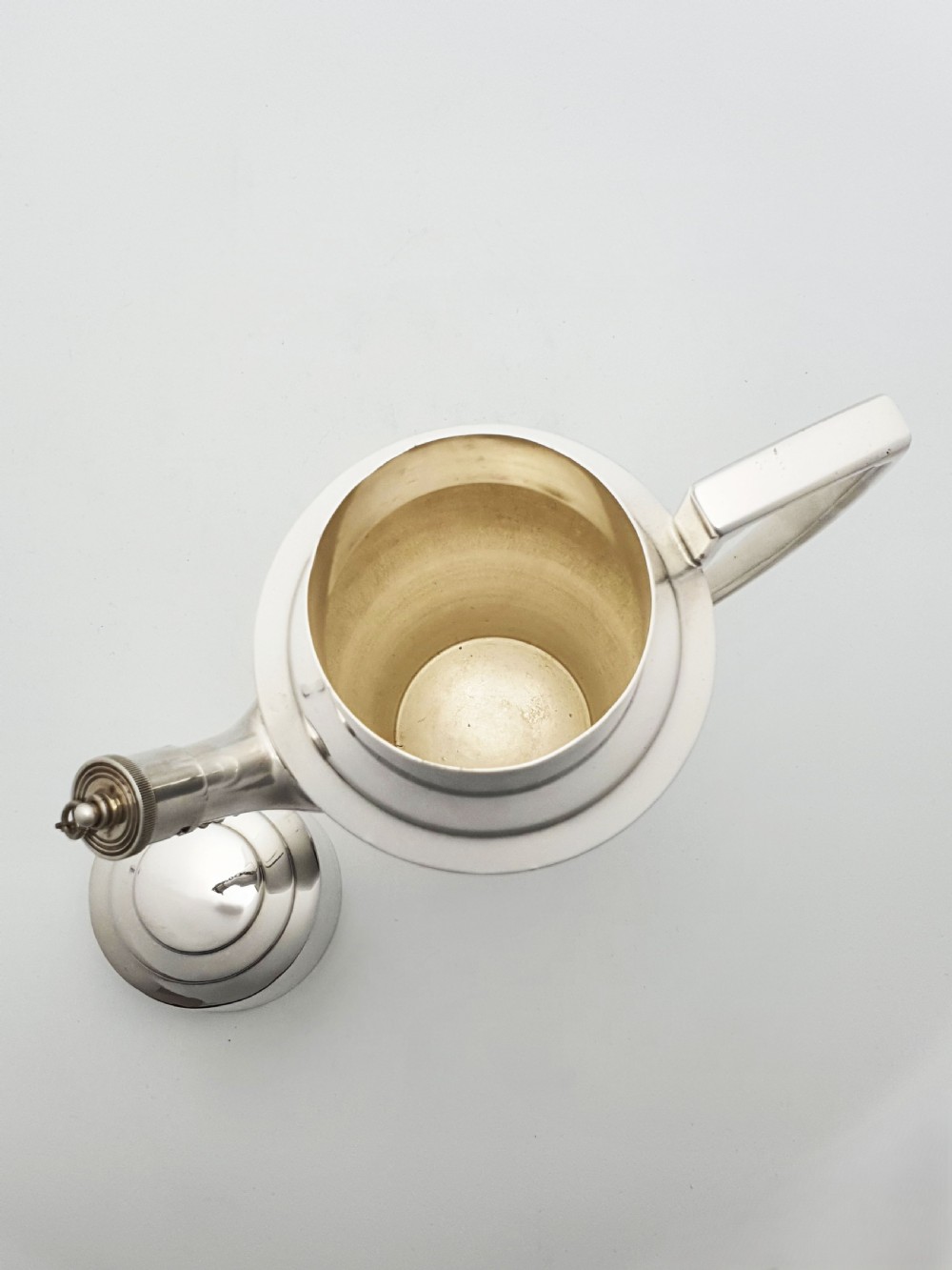An Art Deco silver-plated cocktail shaker featuring a tapered body with concentric ring engravings, a spout with a chained cap, and an angular handle. View V