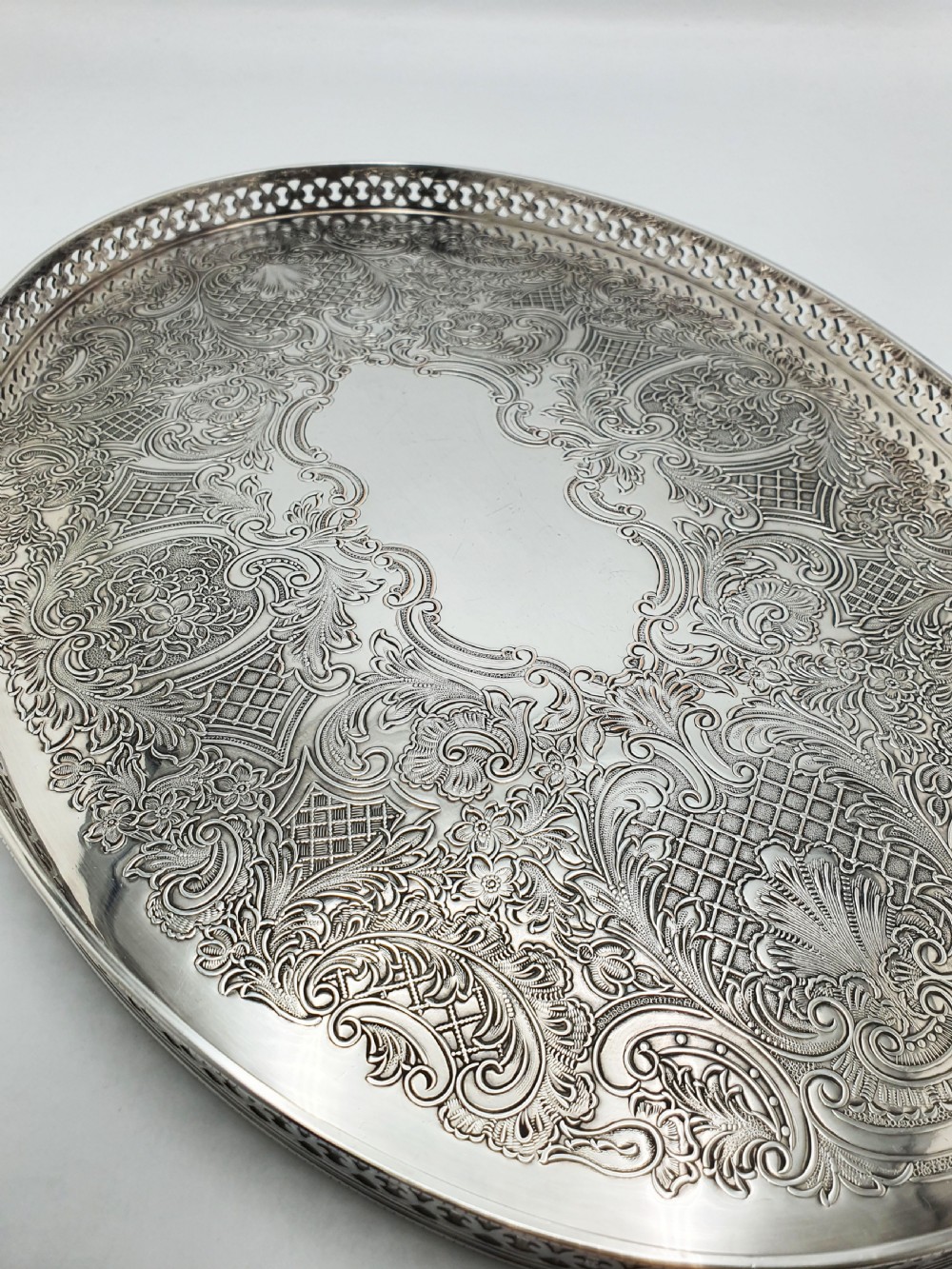 An oval silver-plated serving tray featuring a pierced gallery rim and an engraved surface with scroll motifs around a plain central cartouche. View II