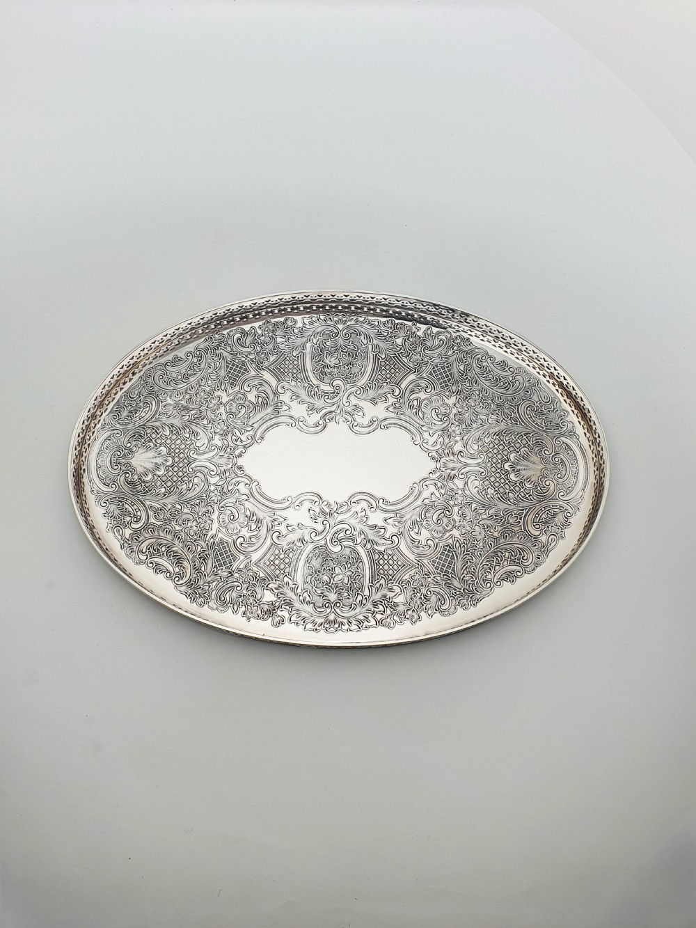 An oval silver-plated serving tray featuring a pierced gallery rim and an engraved surface with scroll motifs around a plain central cartouche. View IV