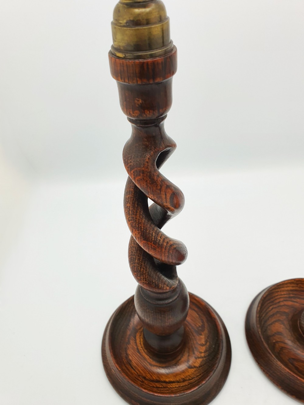 A pair of dark oak candlesticks featuring open barley twist shafts, circular stepped bases, and metal brass sconces. View IV