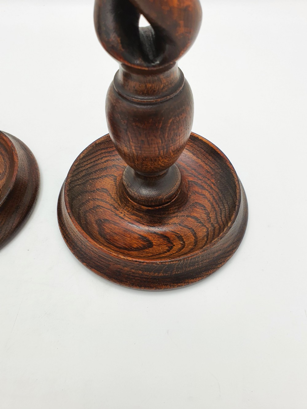 A pair of dark oak candlesticks featuring open barley twist shafts, circular stepped bases, and metal brass sconces. View VI