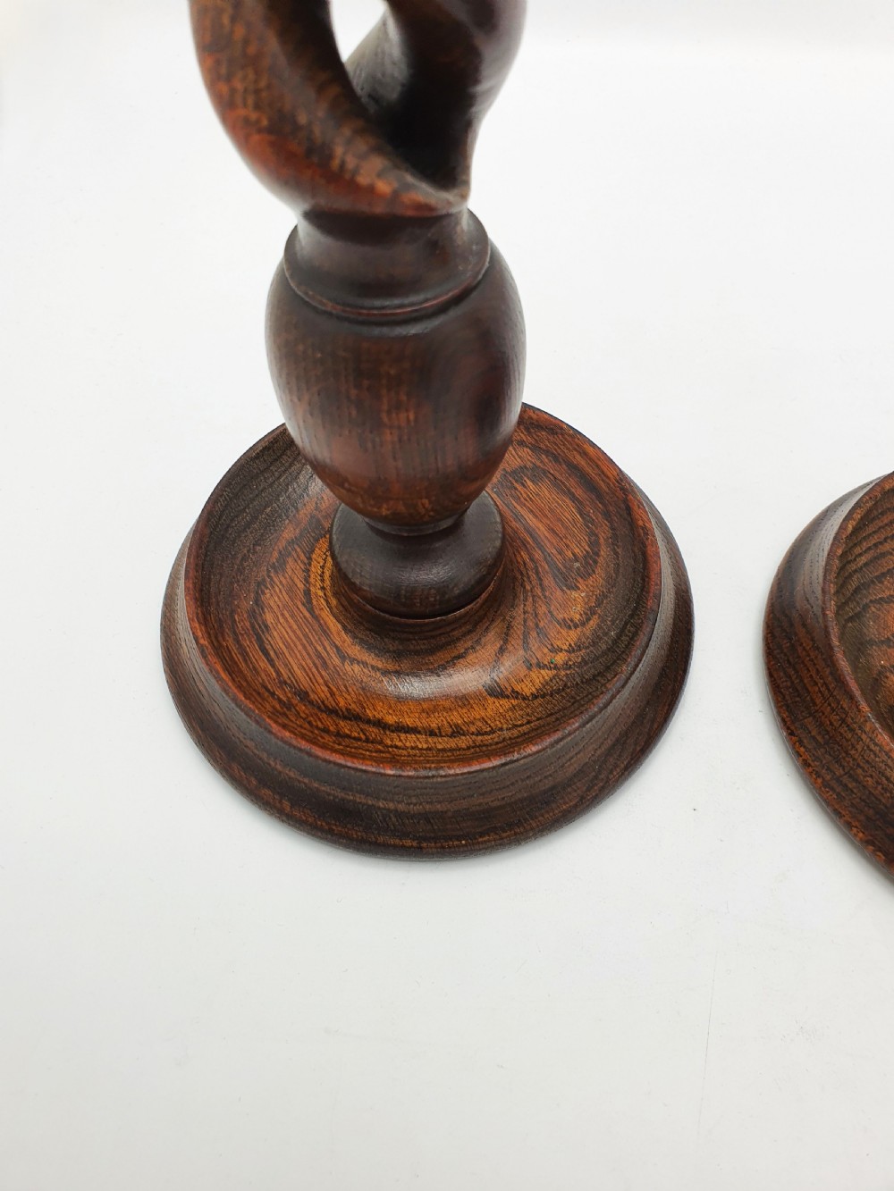 A pair of dark oak candlesticks featuring open barley twist shafts, circular stepped bases, and metal brass sconces. View VII