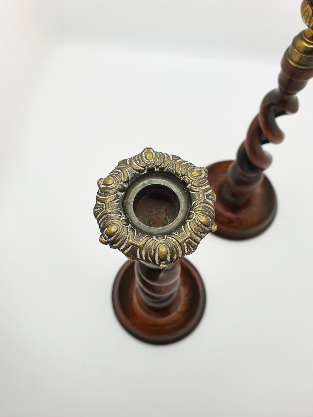 A pair of dark oak candlesticks featuring open barley twist shafts, circular stepped bases, and metal brass sconces. View VIII