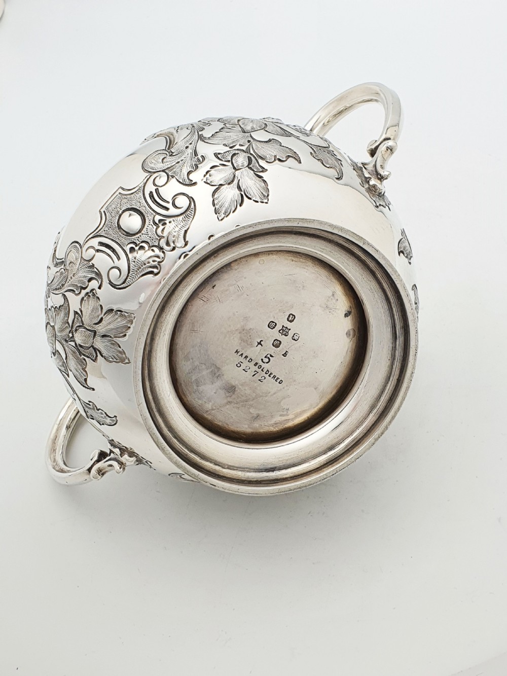 A two-piece Victorian silver-plated set featuring a milk jug and a double-handled sugar bowl, both decorated with intricate repousse floral scrollwork and lined with a gilded interior. View VII