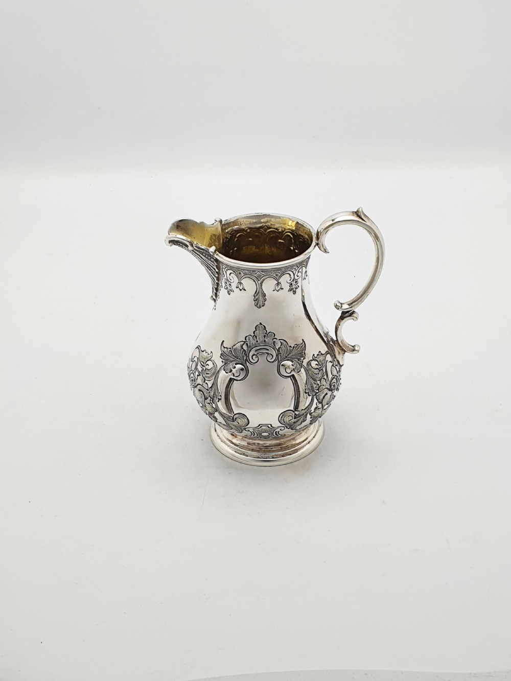 A two-piece Victorian silver-plated set featuring a milk jug and a double-handled sugar bowl, both decorated with intricate repousse floral scrollwork and lined with a gilded interior. View VIII