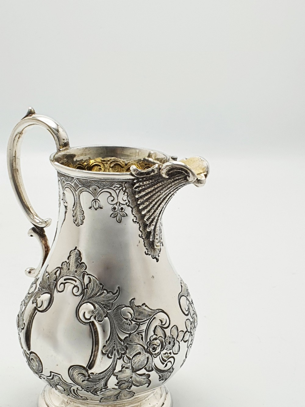 A two-piece Victorian silver-plated set featuring a milk jug and a double-handled sugar bowl, both decorated with intricate repousse floral scrollwork and lined with a gilded interior. View XIII