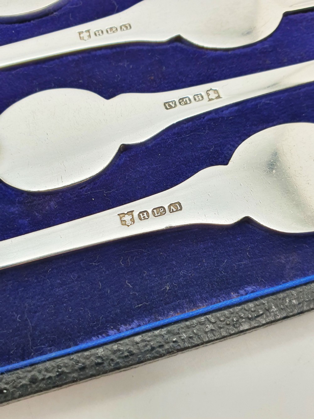 A cased set of six silver-plated lobster picks displayed inside a dark blue velvet-lined presentation box. View II