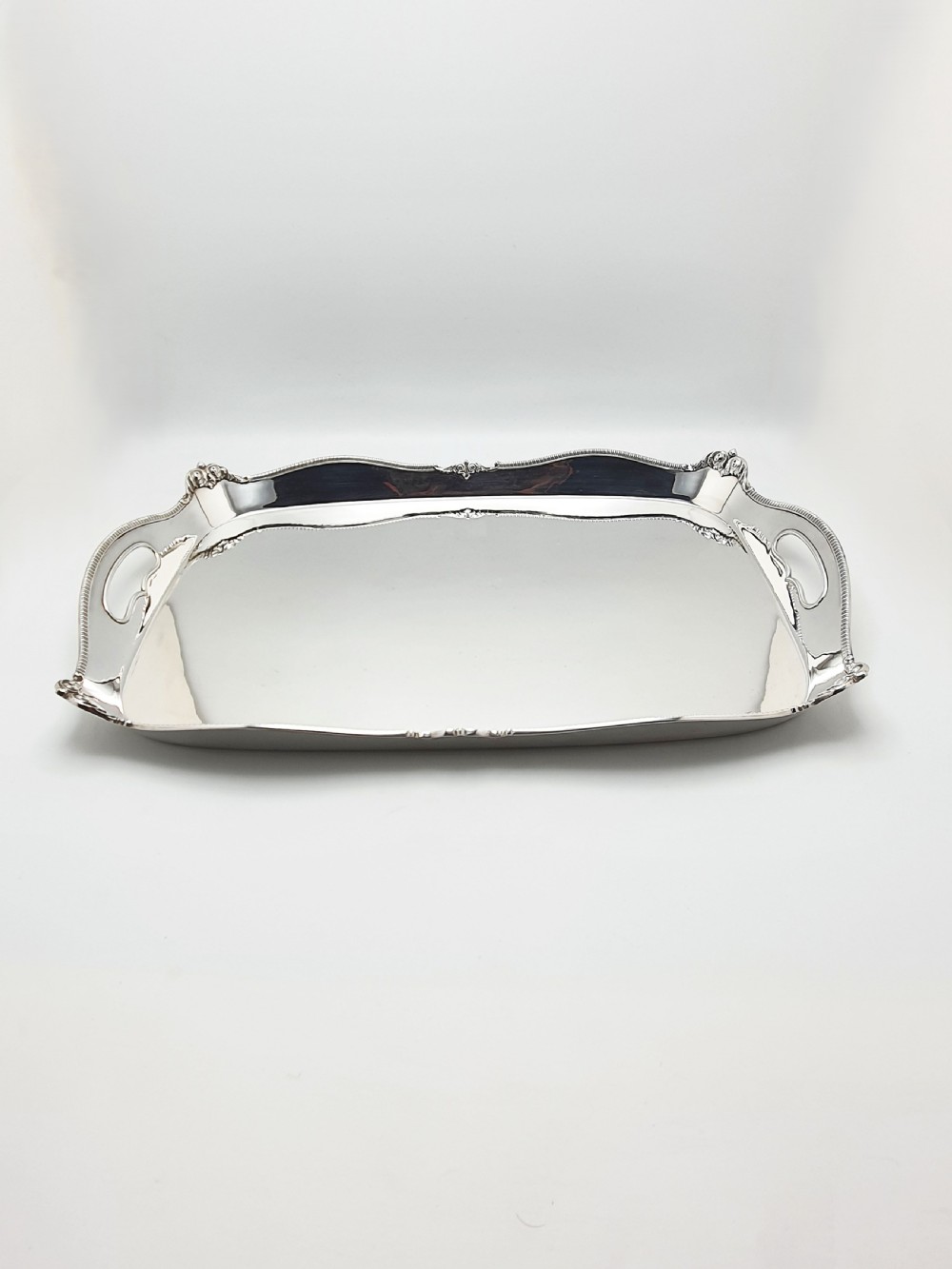 An Edwardian rectangular silver-plated serving tray featuring raised sides, integral hand-holds, and decorative shell and scroll details along the rim. View IV