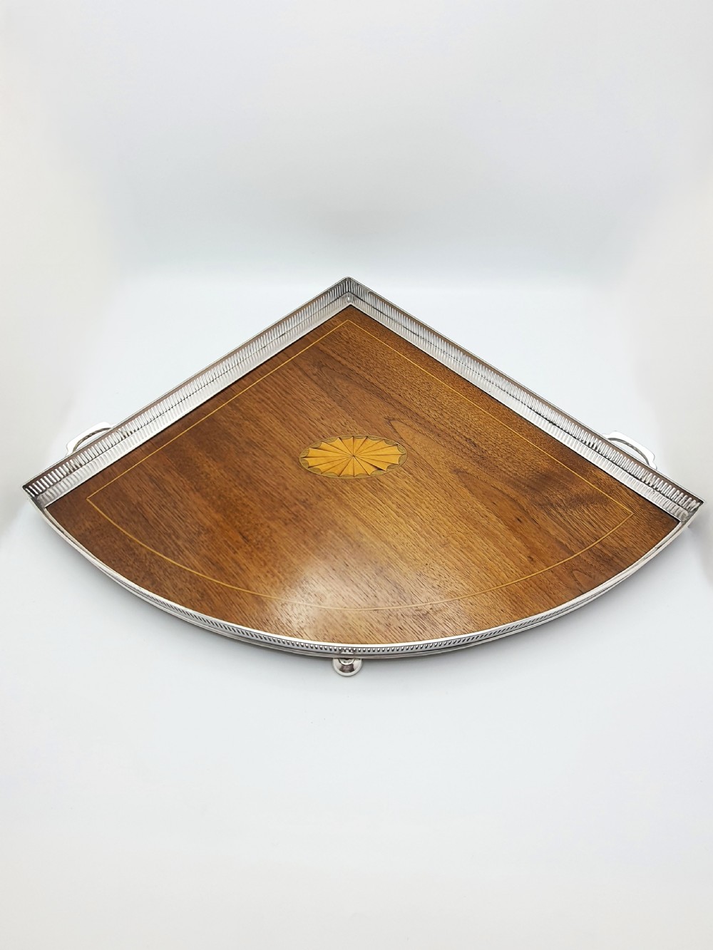 A fan-shaped Edwardian mahogany serving tray featuring an inlaid oval patera motif, fine line stringing, and a pierced silver-plated gallery rim with handles and ball feet. View III