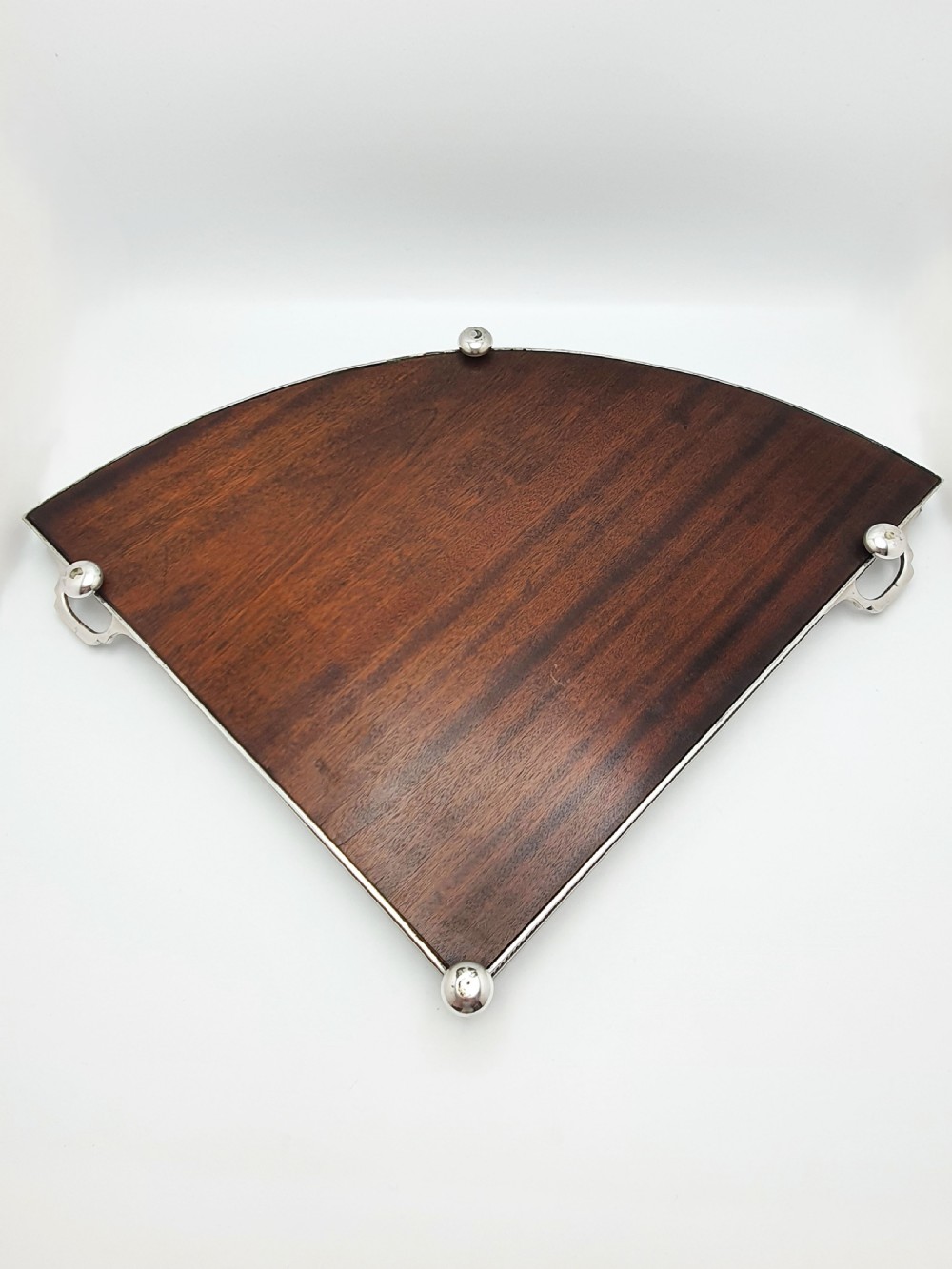 A fan-shaped Edwardian mahogany serving tray featuring an inlaid oval patera motif, fine line stringing, and a pierced silver-plated gallery rim with handles and ball feet. View IX