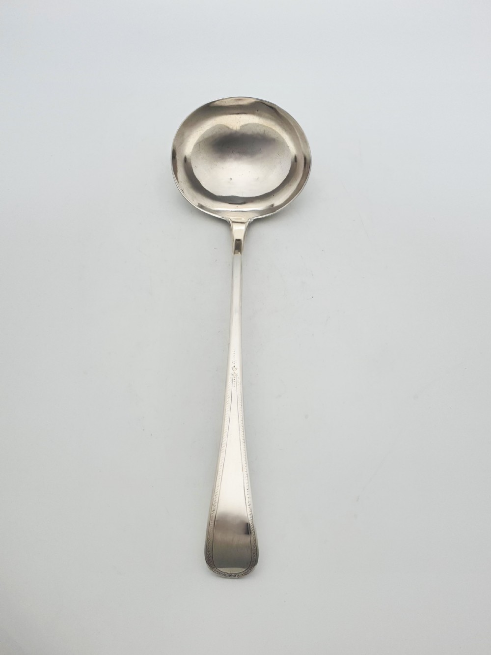 A Georgian sterling silver soup ladle dated 1824 featuring a long tapered handle with a subtle threaded border and a deep oval bowl. View III