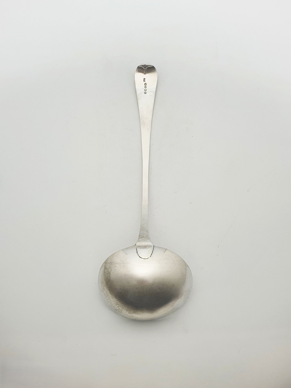 A Georgian sterling silver soup ladle dated 1824 featuring a long tapered handle with a subtle threaded border and a deep oval bowl. View IV