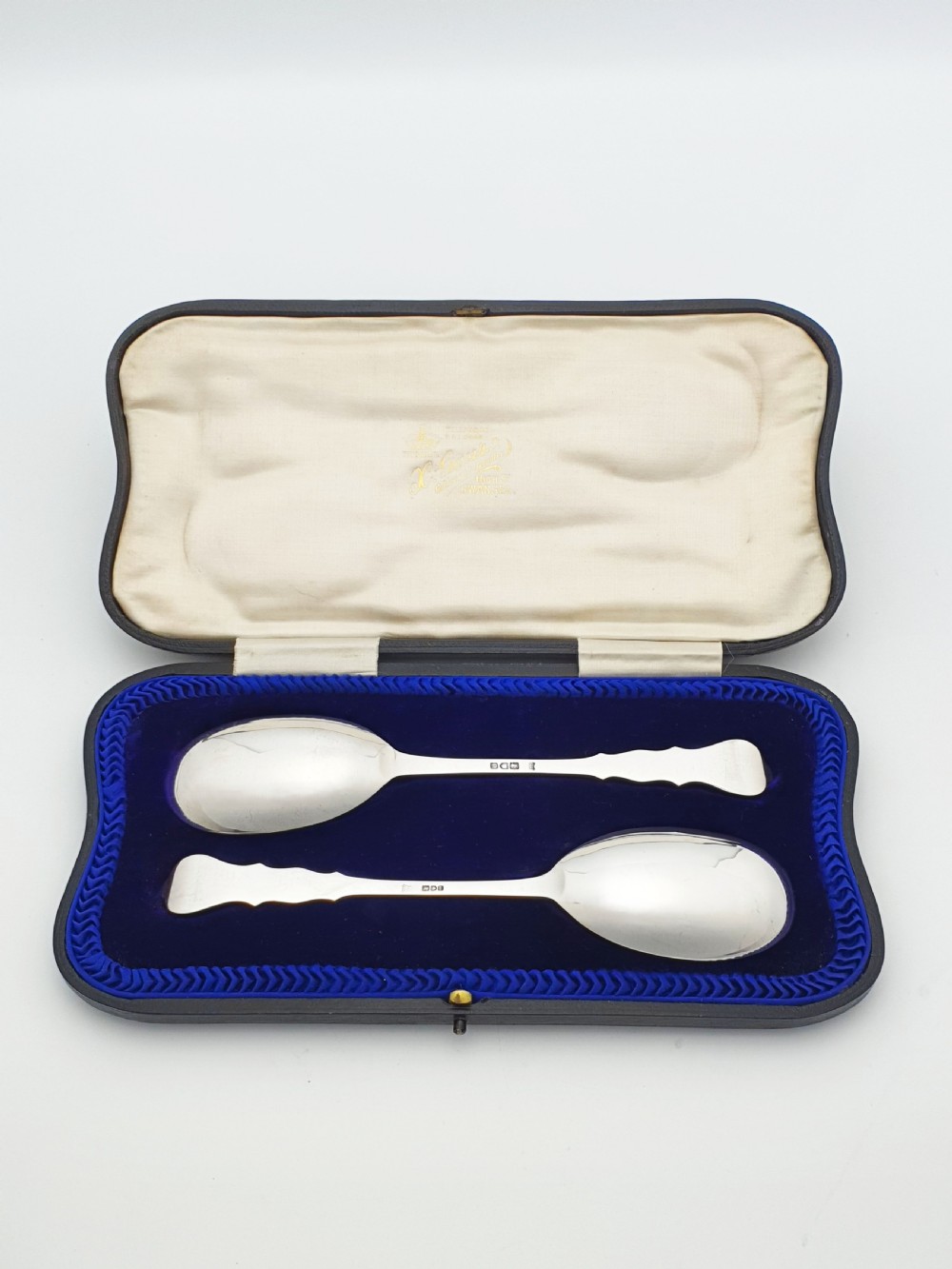A pair of 1910 sterling silver serving spoons with gilt oval bowls presented inside a dark blue velvet-lined case. View II