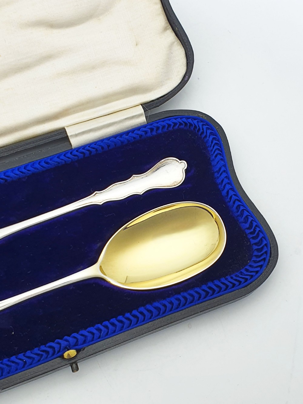 A pair of 1910 sterling silver serving spoons with gilt oval bowls presented inside a dark blue velvet-lined case. View IV