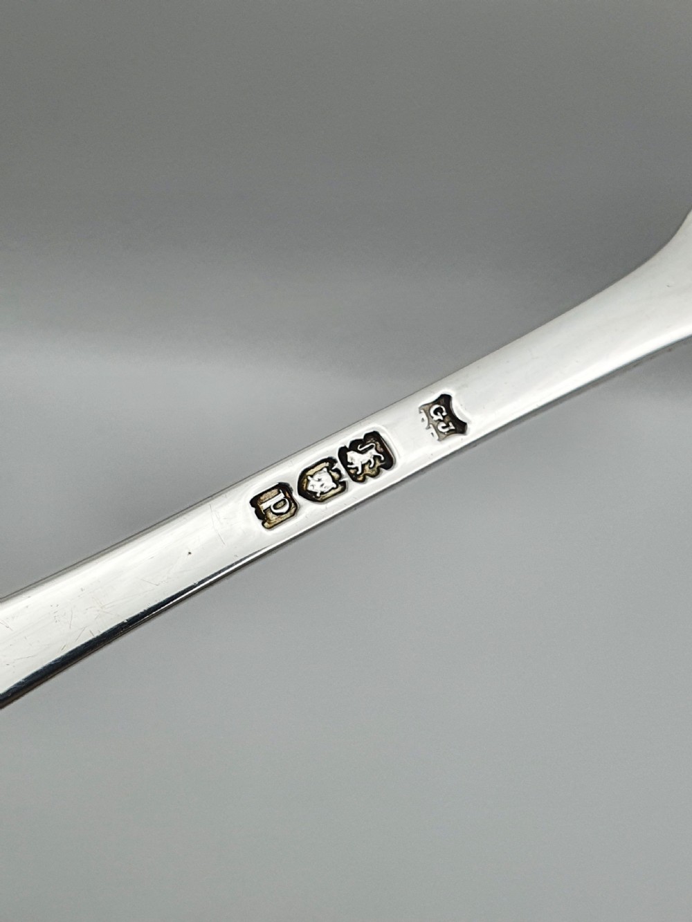 A pair of 1910 sterling silver serving spoons with gilt oval bowls presented inside a dark blue velvet-lined case. View V