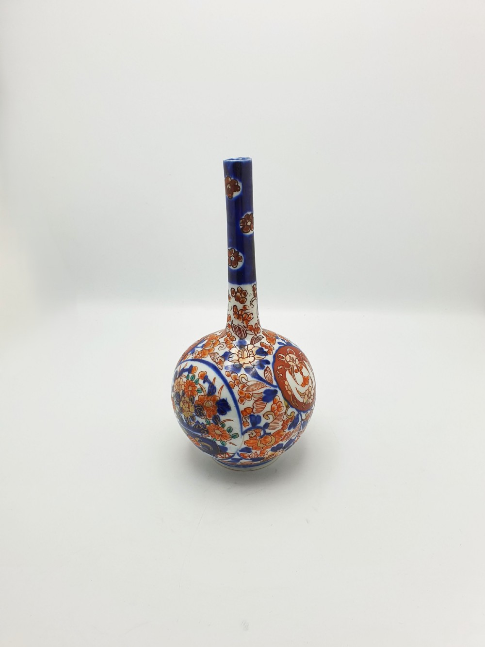 A Japanese Imari porcelain vase with a long slender neck and bulbous body hand-painted with cobalt blue and iron-red floral patterns.