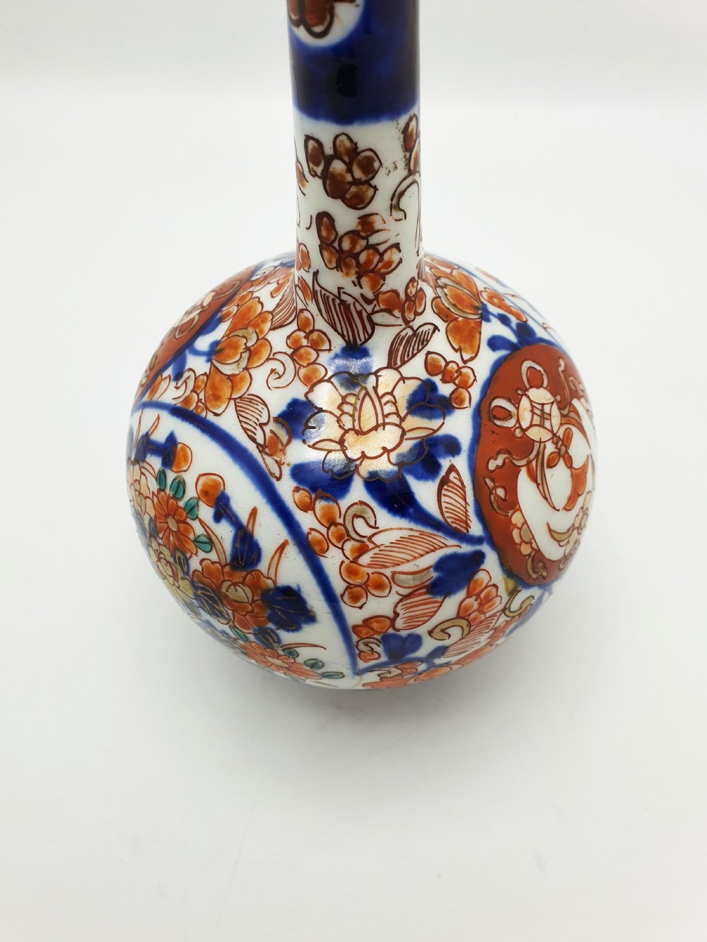 A Japanese Imari porcelain vase with a long slender neck and bulbous body hand-painted with cobalt blue and iron-red floral patterns. View II