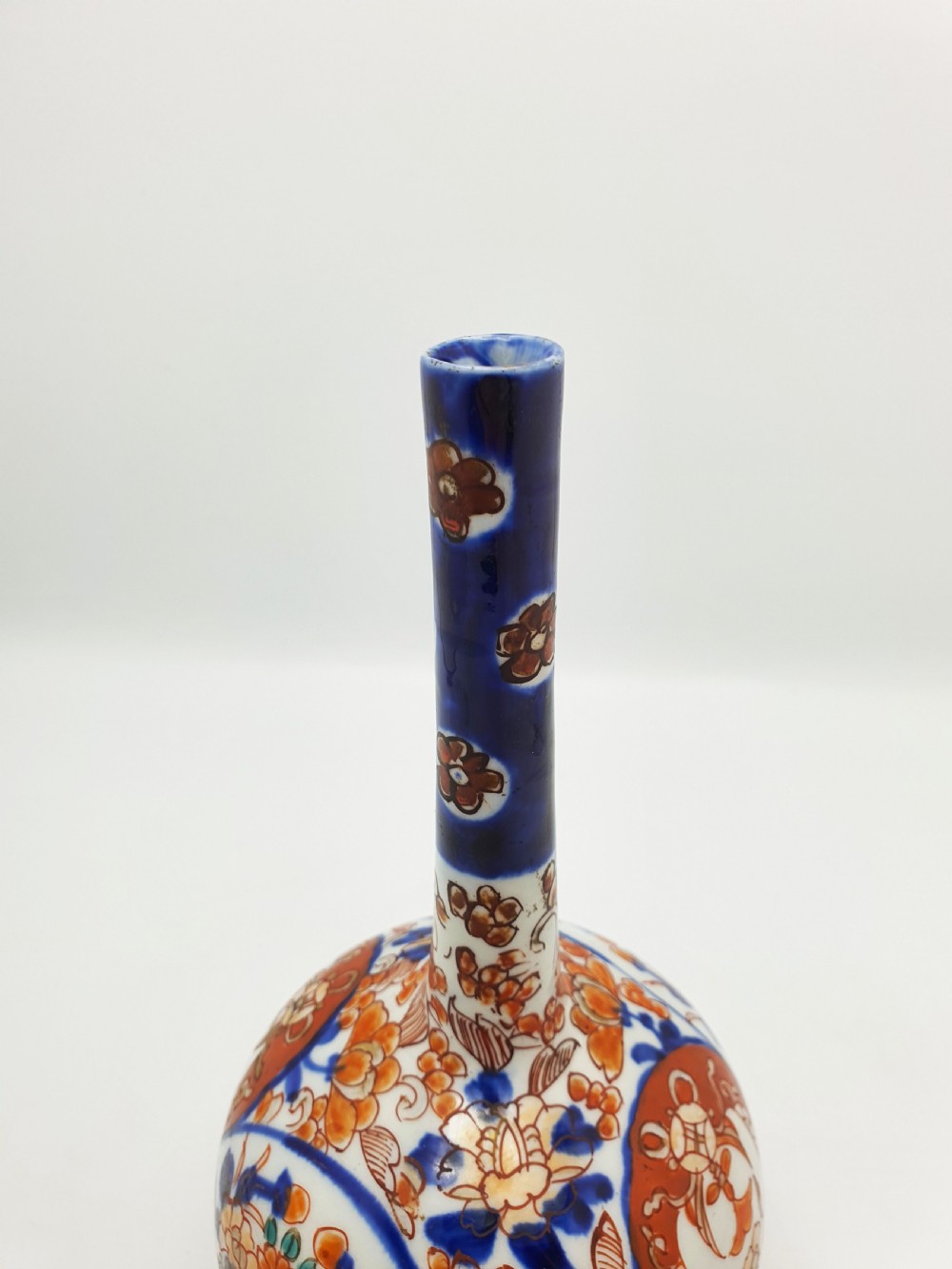 A Japanese Imari porcelain vase with a long slender neck and bulbous body hand-painted with cobalt blue and iron-red floral patterns. View III