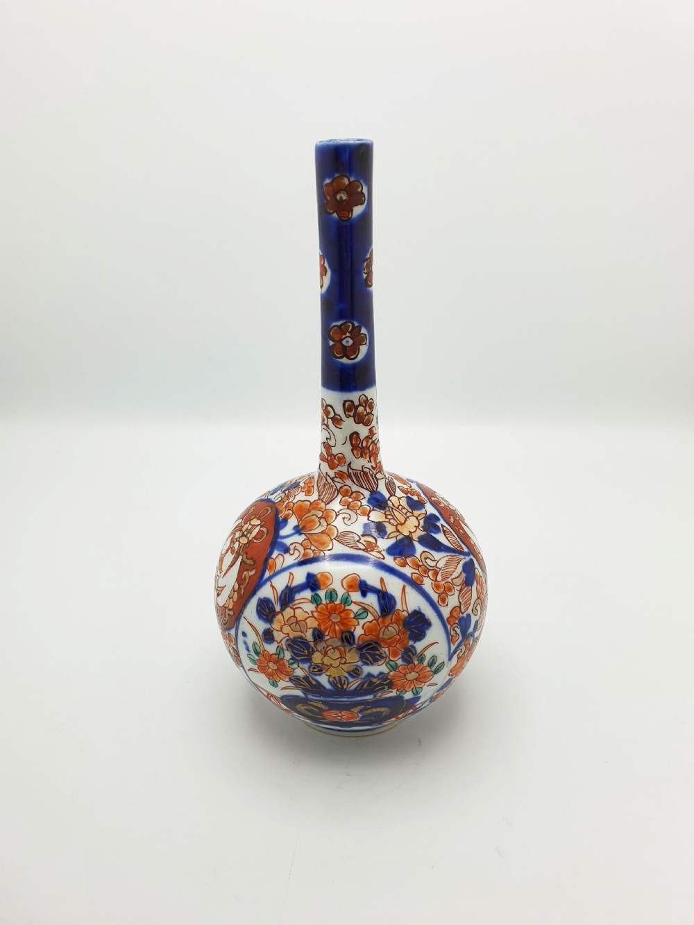 A Japanese Imari porcelain vase with a long slender neck and bulbous body hand-painted with cobalt blue and iron-red floral patterns. View IV