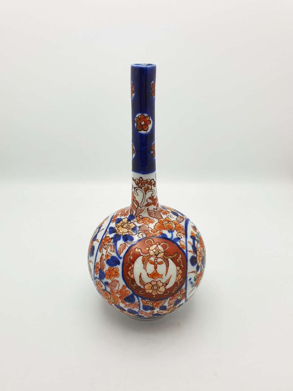 A Japanese Imari porcelain vase with a long slender neck and bulbous body hand-painted with cobalt blue and iron-red floral patterns. View V
