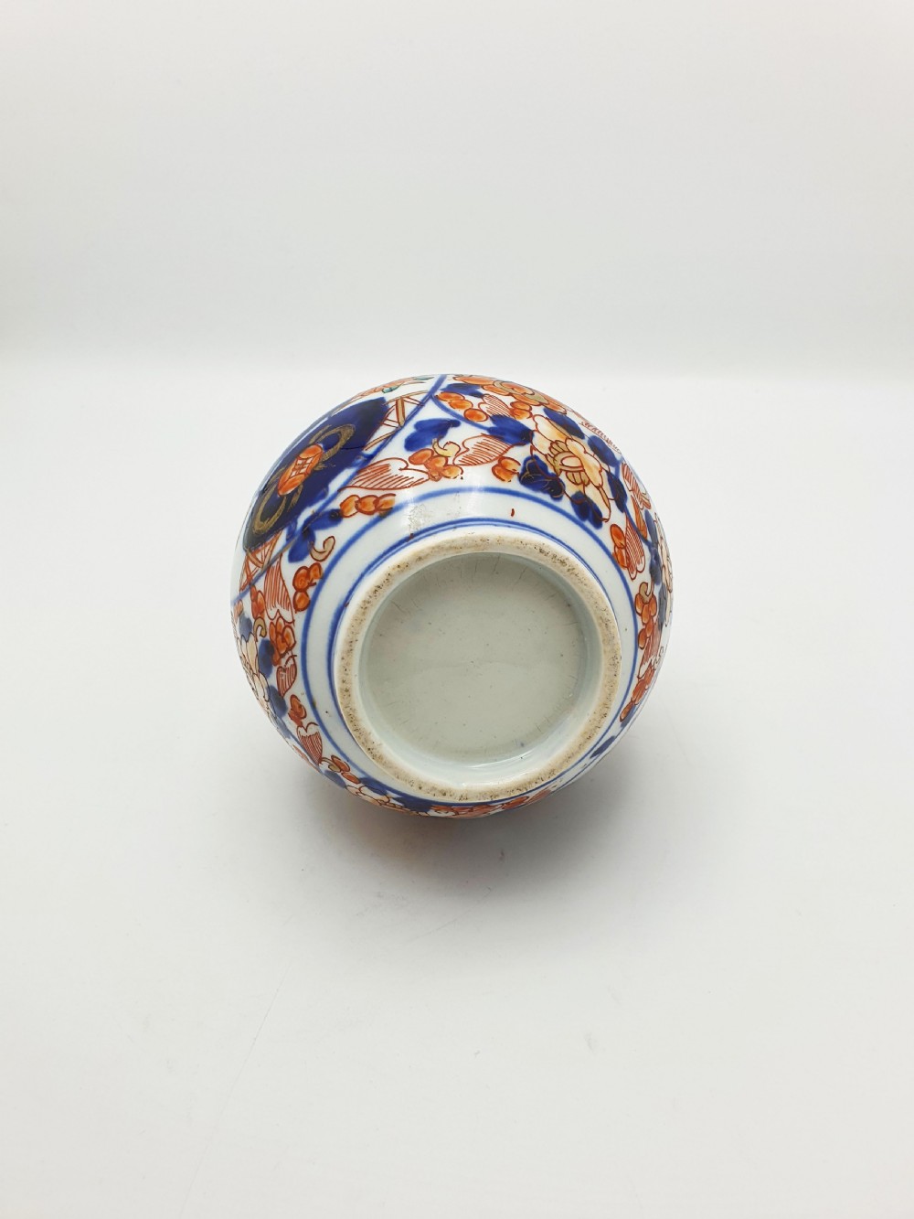 A Japanese Imari porcelain vase with a long slender neck and bulbous body hand-painted with cobalt blue and iron-red floral patterns. View VI