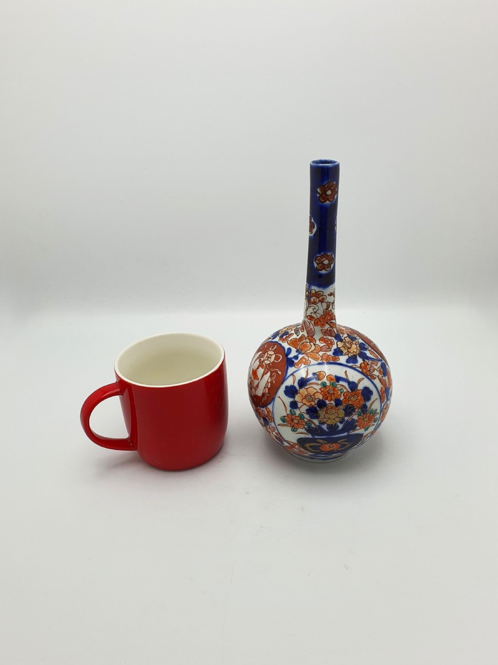 A Japanese Imari porcelain vase with a long slender neck and bulbous body hand-painted with cobalt blue and iron-red floral patterns. View VII