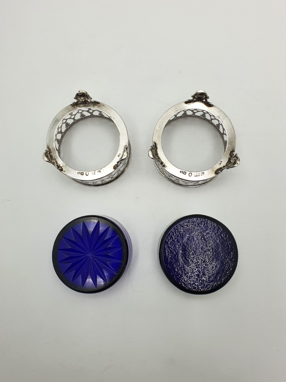 A pair of circular pierced sterling silver salt cellars containing dark cobalt blue glass liners with accompanying engraved silver spoons. View XI