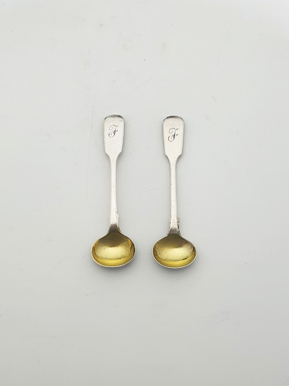 A pair of circular pierced sterling silver salt cellars containing dark cobalt blue glass liners with accompanying engraved silver spoons. View XIV