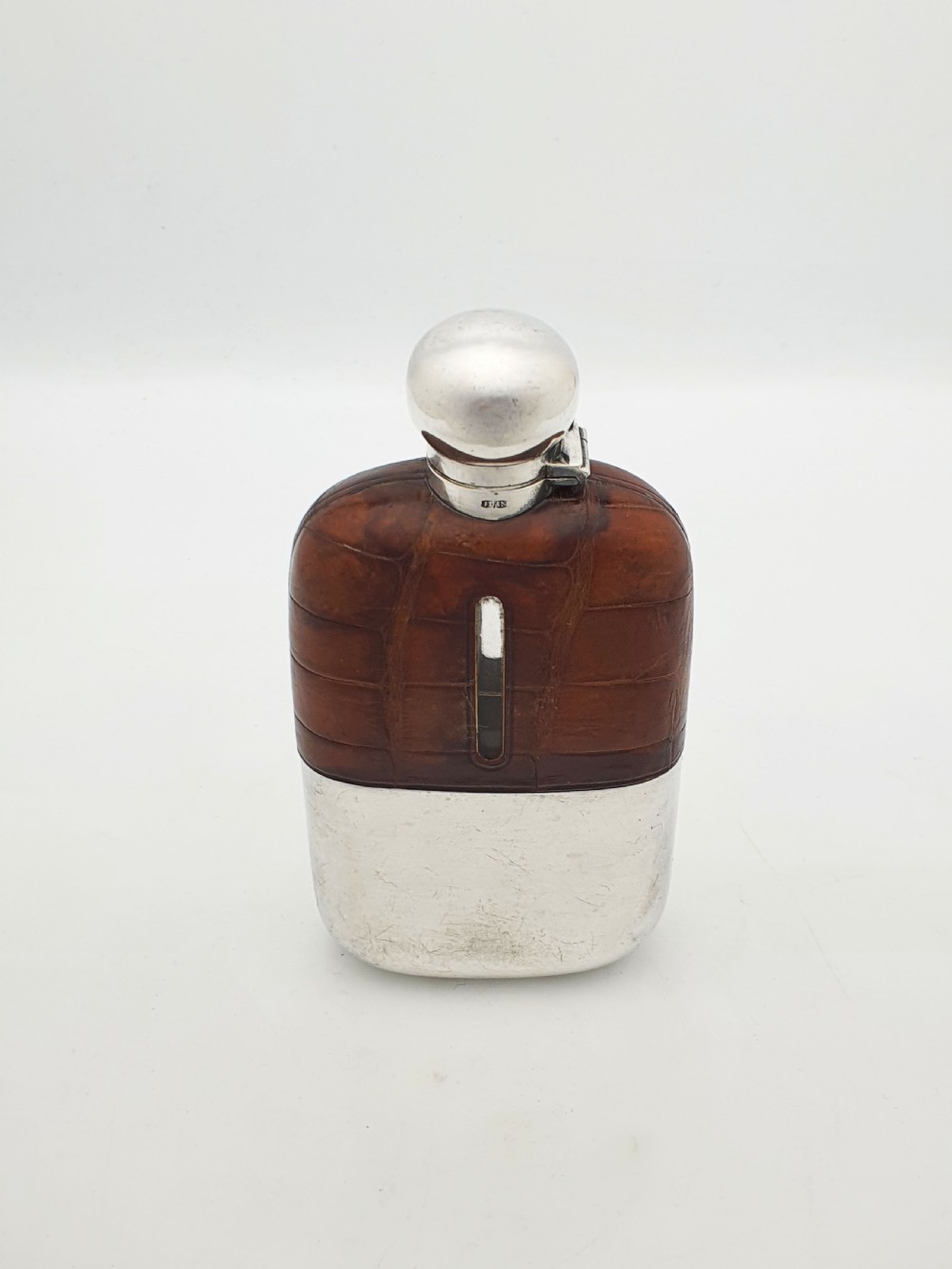 An antique Edwardian hip flask featuring a brown crocodile skin upper section with a vertical sight slot and a silver-plated lower removable cup.