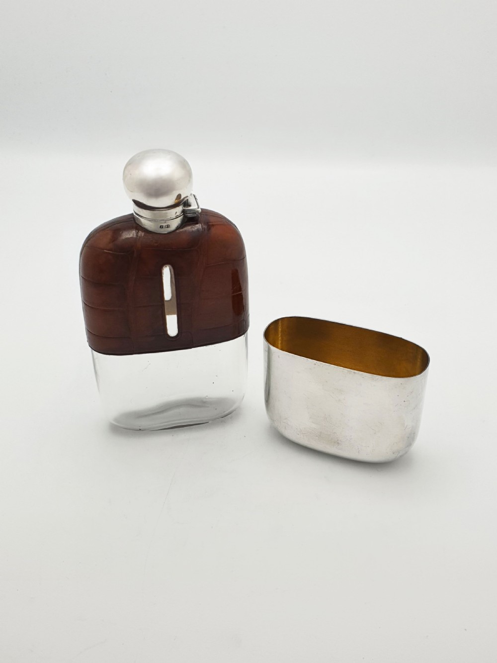An antique Edwardian hip flask featuring a brown crocodile skin upper section with a vertical sight slot and a silver-plated lower removable cup. View V