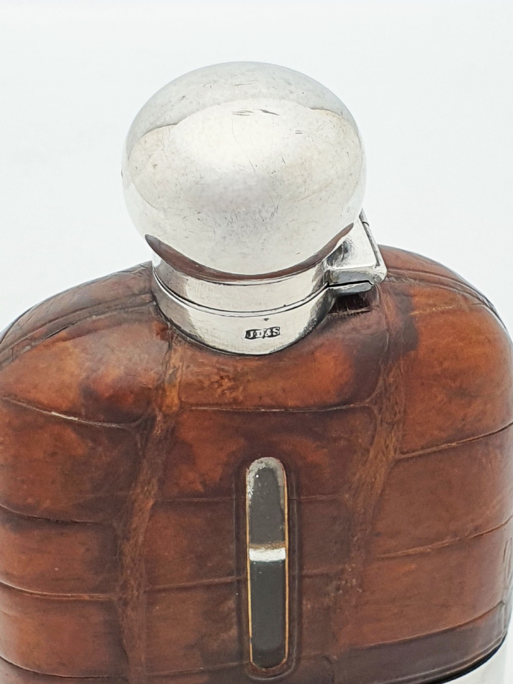 An antique Edwardian hip flask featuring a brown crocodile skin upper section with a vertical sight slot and a silver-plated lower removable cup. View VII