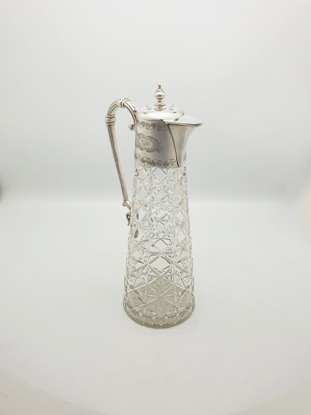 A tall Victorian cut glass claret jug featuring geometric diamond-cut motifs and an engraved silver-plated mount with a hinged lid and scrolled handle. View III