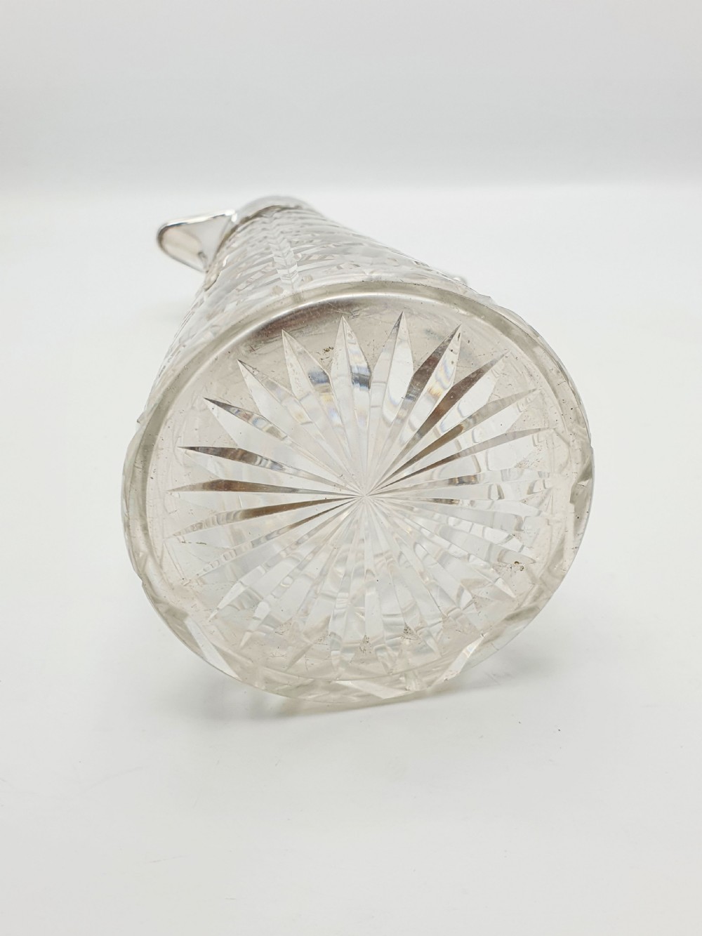 A tall Victorian cut glass claret jug featuring geometric diamond-cut motifs and an engraved silver-plated mount with a hinged lid and scrolled handle. View VIII