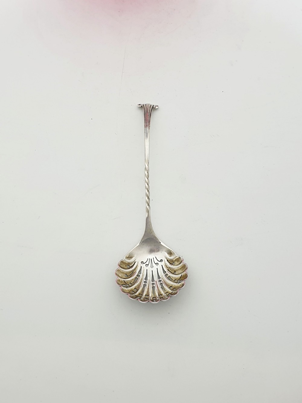 A Victorian cranberry glass bowl with a crimped rim and applied feet, containing a metal pierced spoon. View VI