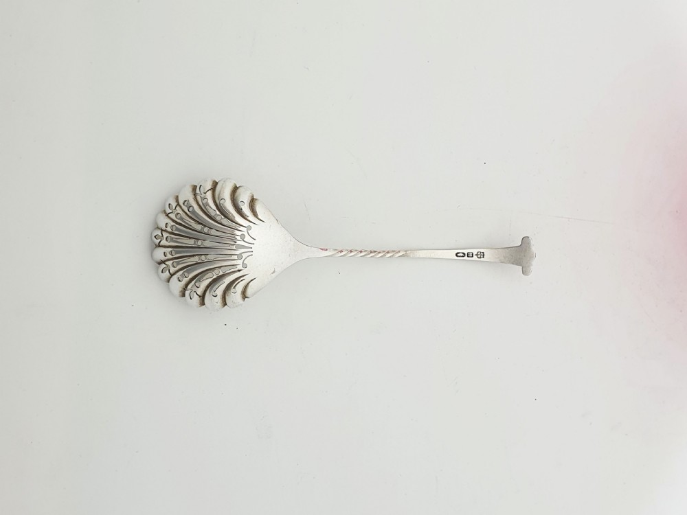A Victorian cranberry glass bowl with a crimped rim and applied feet, containing a metal pierced spoon. View VIII
