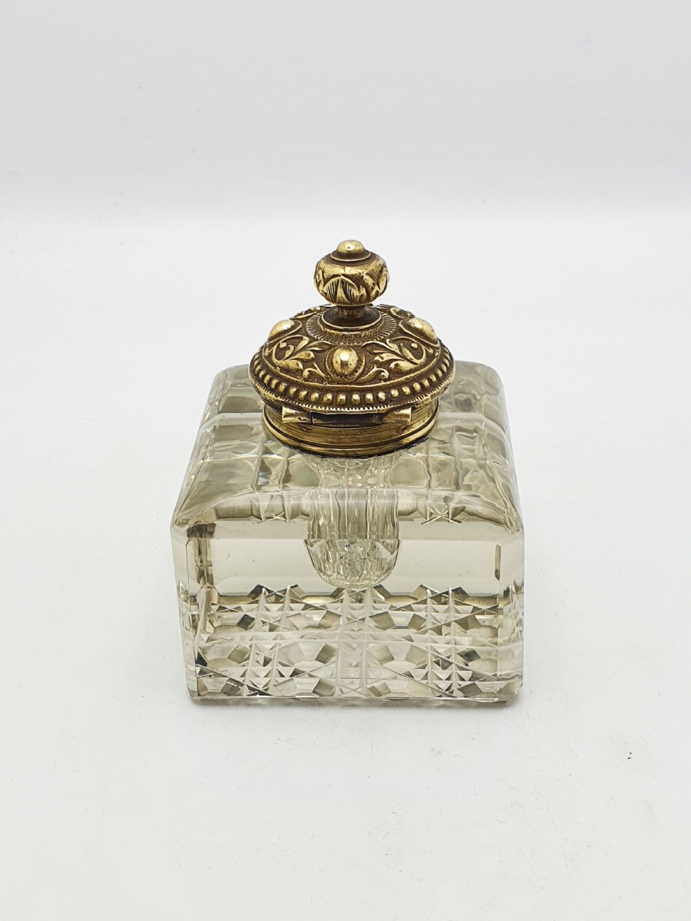 A square, heavy cut-glass antique inkwell featuring a diamond pattern and an ornate, embossed brass hinged lid. View VII