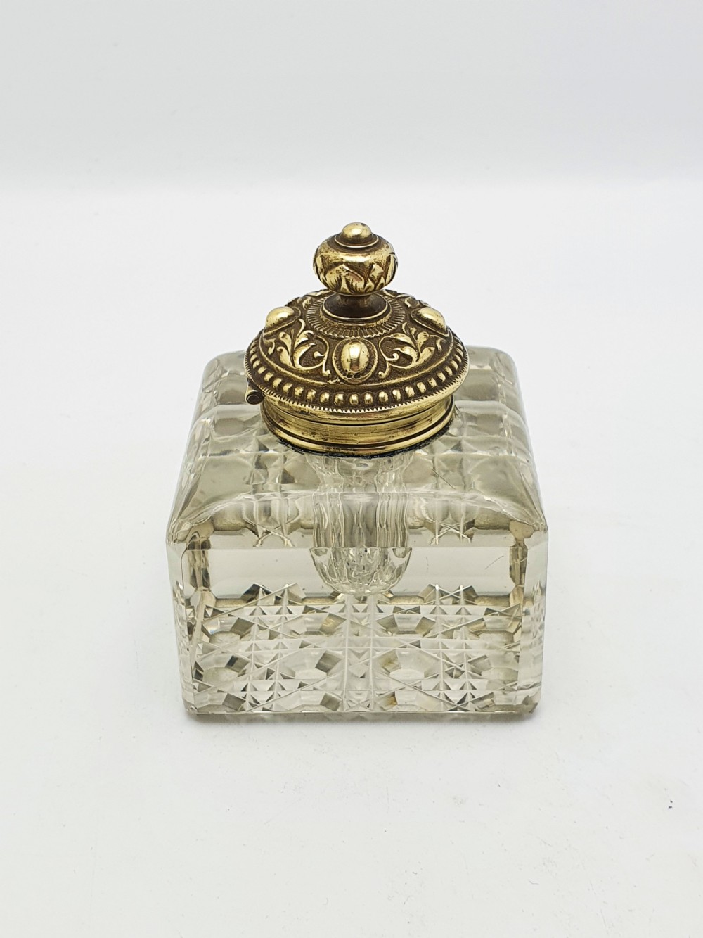 A square, heavy cut-glass antique inkwell featuring a diamond pattern and an ornate, embossed brass hinged lid. View VIII