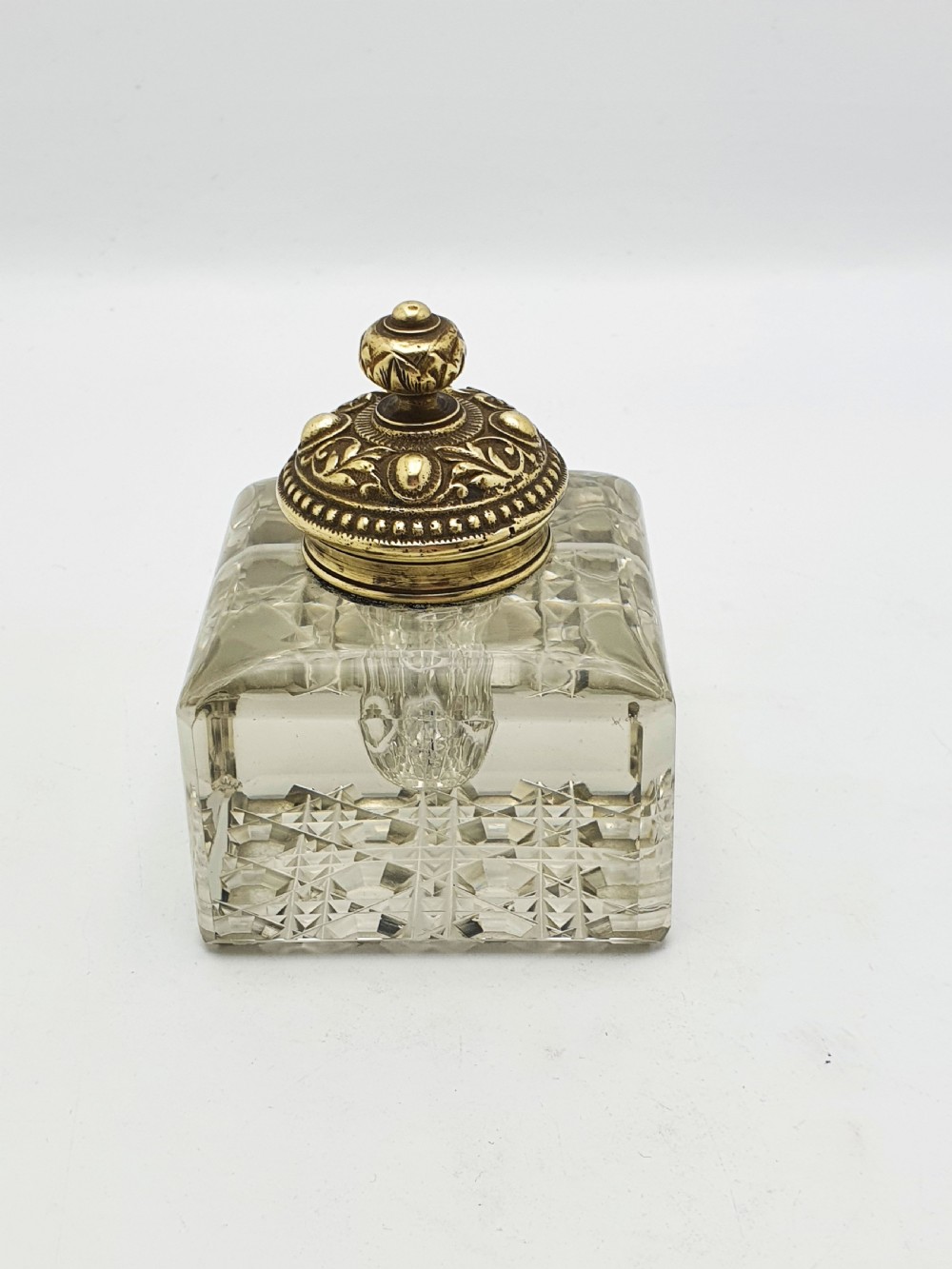 A square, heavy cut-glass antique inkwell featuring a diamond pattern and an ornate, embossed brass hinged lid. View IX
