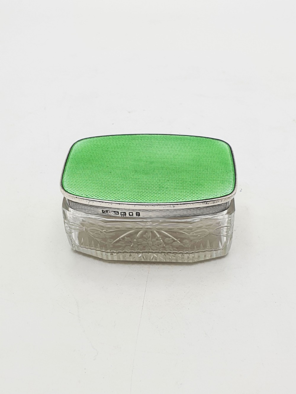 A rectangular clear etched glass dressing table jar topped with a sterling silver rim and a bright green guilloche enamel lid. View III