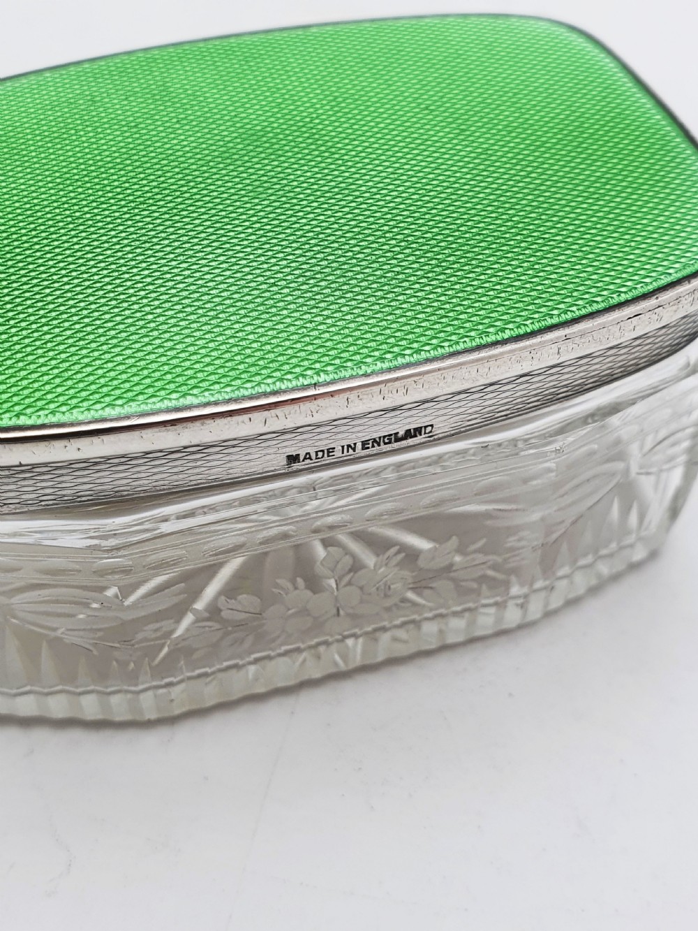 A rectangular clear etched glass dressing table jar topped with a sterling silver rim and a bright green guilloche enamel lid. View VIII