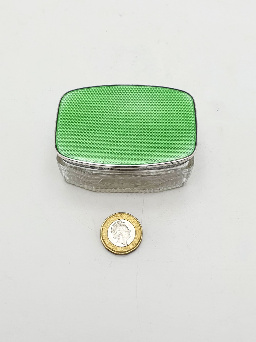 A rectangular clear etched glass dressing table jar topped with a sterling silver rim and a bright green guilloche enamel lid. View XII
