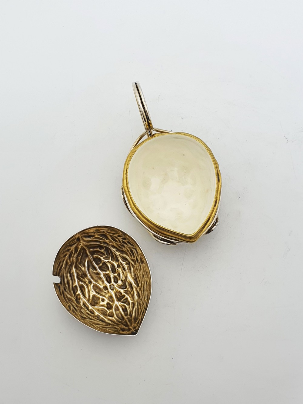 A late Victorian walnut-shaped metal condiment container featuring a textured silver lid and a brass lower shell resting within a wirework stand with a handle. View VII