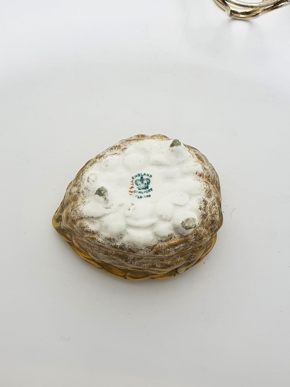 A late Victorian walnut-shaped metal condiment container featuring a textured silver lid and a brass lower shell resting within a wirework stand with a handle. View IX