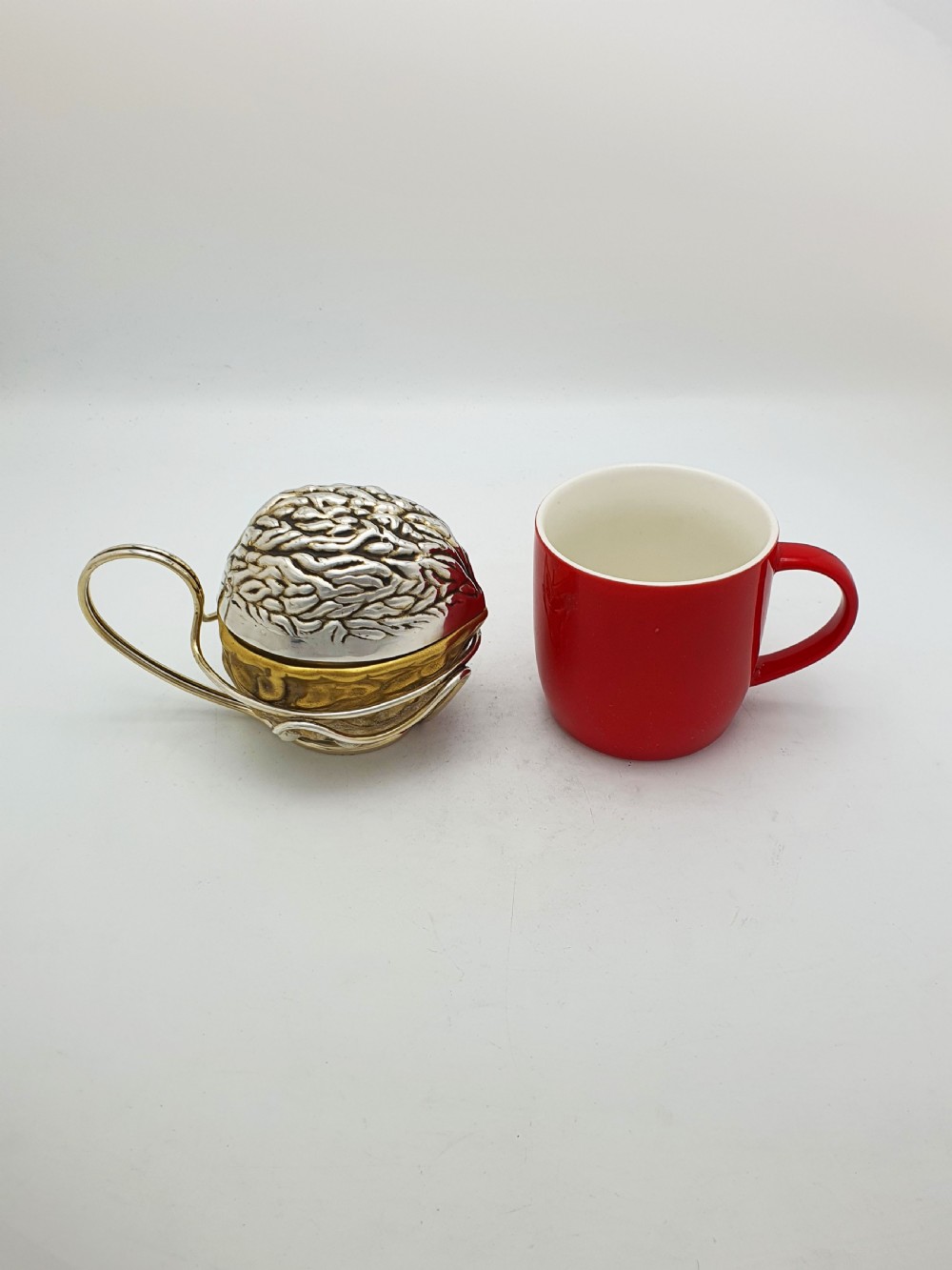 A late Victorian walnut-shaped metal condiment container featuring a textured silver lid and a brass lower shell resting within a wirework stand with a handle. View XII