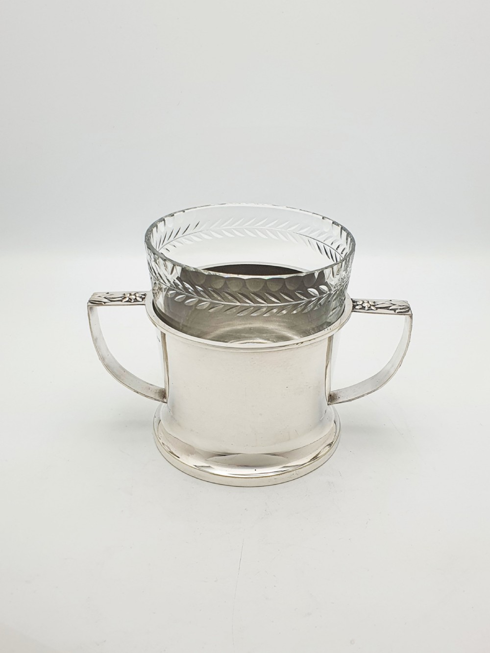 An Art Deco silver-plated ice bucket featuring twin handles, a removable cut-glass liner with a leaf pattern, and matching ice tongs. View IV