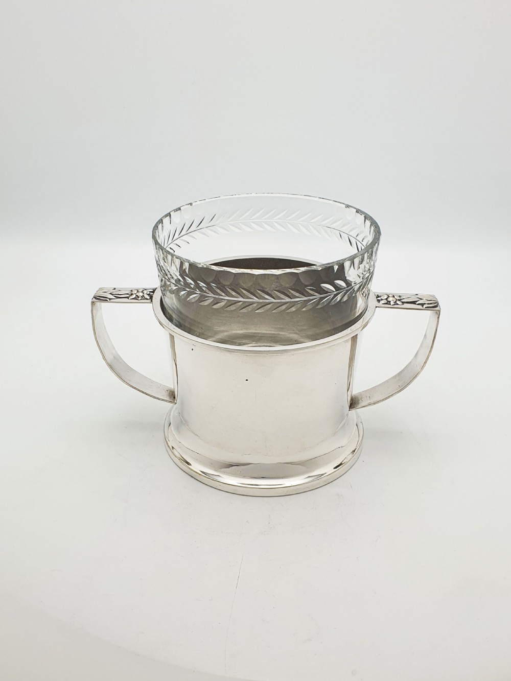 An Art Deco silver-plated ice bucket featuring twin handles, a removable cut-glass liner with a leaf pattern, and matching ice tongs. View V